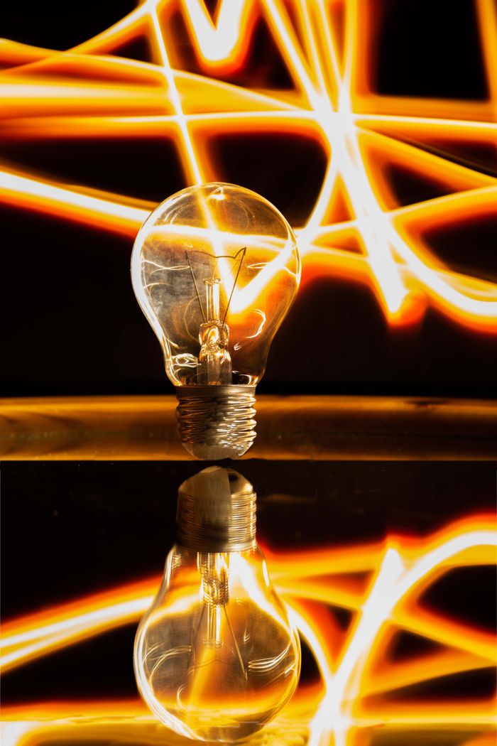 Crafting Captivating Headlines: Your awesome post title goes here Close-up of an illuminated light bulb with neon light streaks and reflection, exuding energy and creativity.