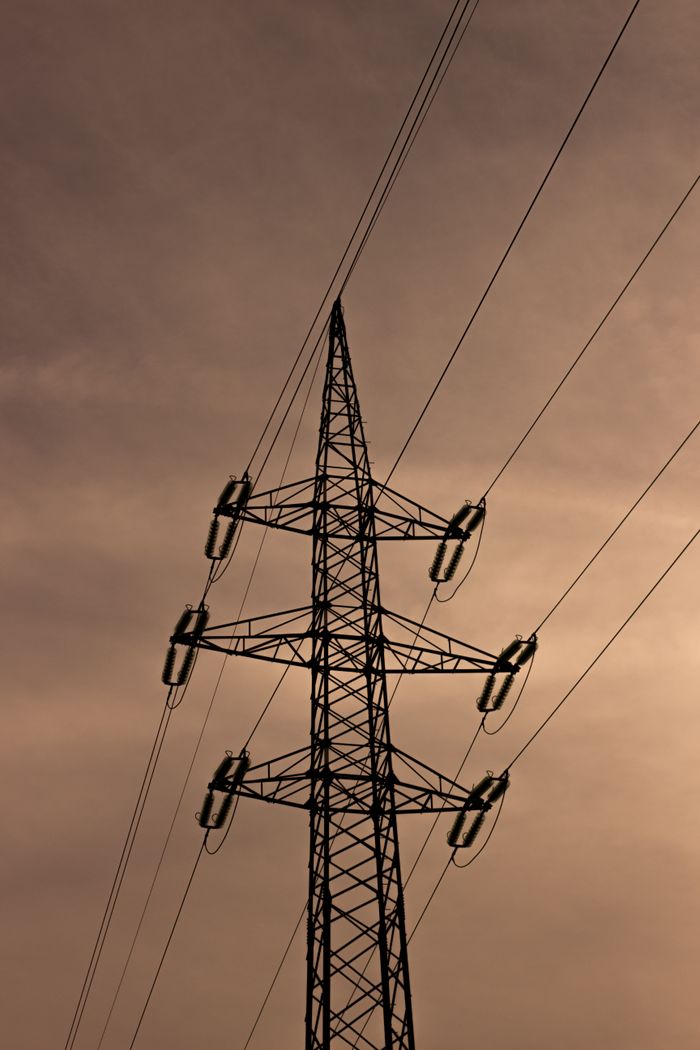 Services Silhouette of an electricity pylon with power lines set against a dramatic sunset sky.