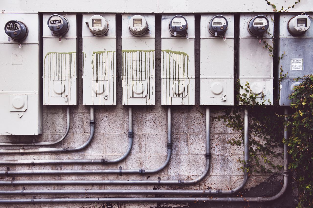 Services Array of outdoor electric meters on a brick wall with vines.
